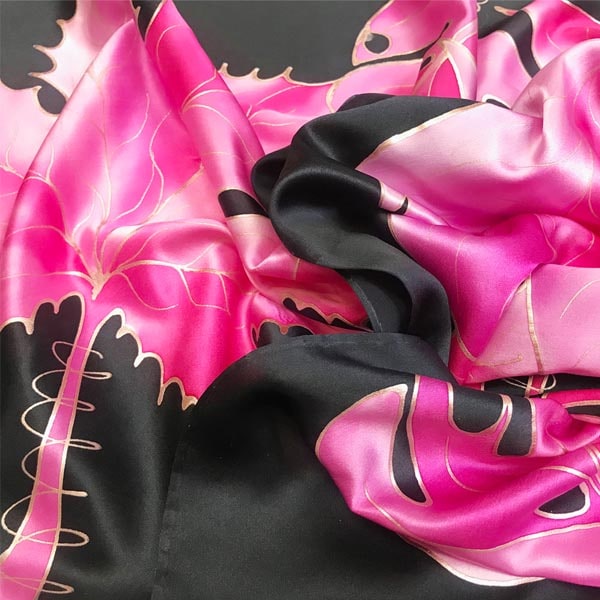 Fular de seda pintado a mano con hojas rosas y fondo negro.